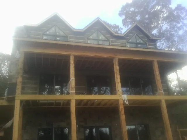 Dormers and porch framing on a large log home under construction — Roof Coating work by our crew in Swansea