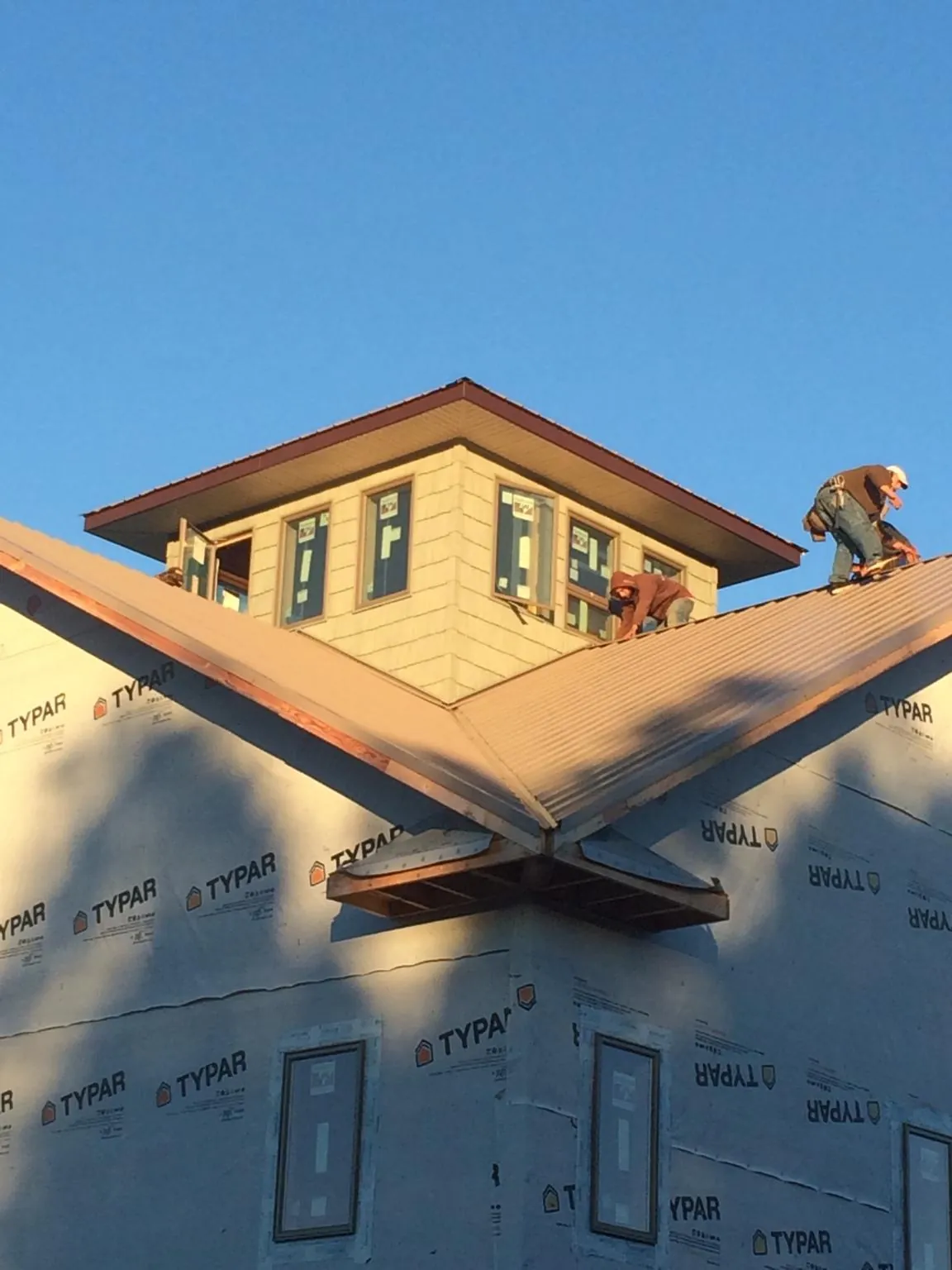 Roofers working around a rooftop cupola on a new metal roof at sunset — Roof Waterproofing in Swansea by Roofing Brothers
